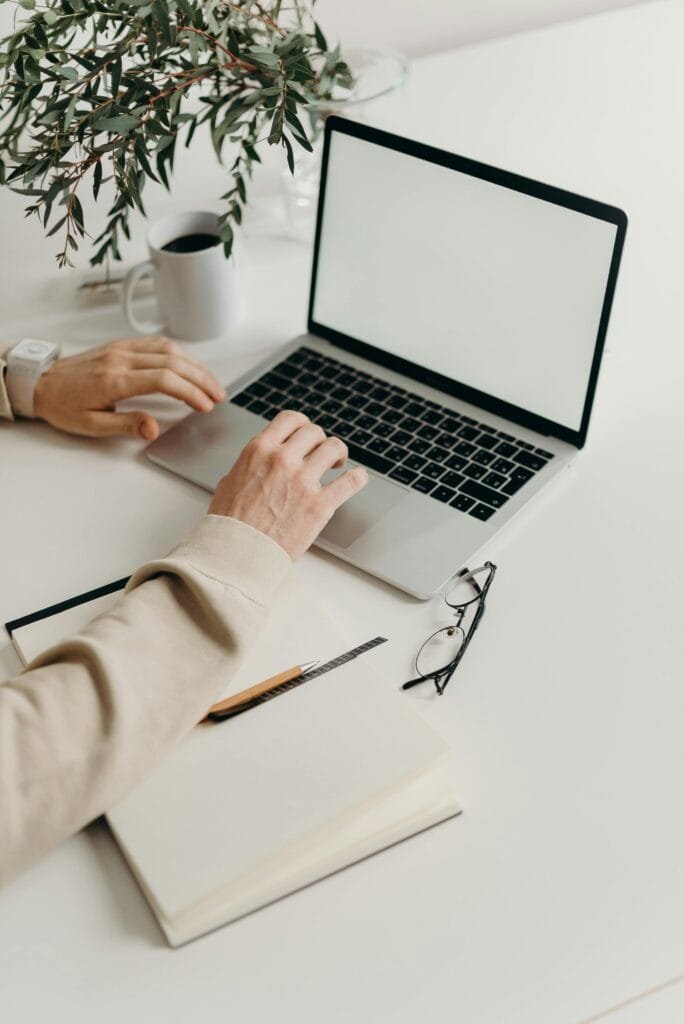 Πληροφορική A clean and modern workspace featuring a laptop, houseplant, and notebook.